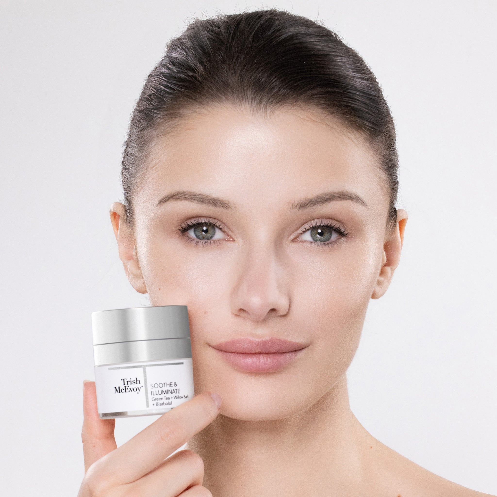 Woman holding a Trish McEvoy skincare product against a plain background
