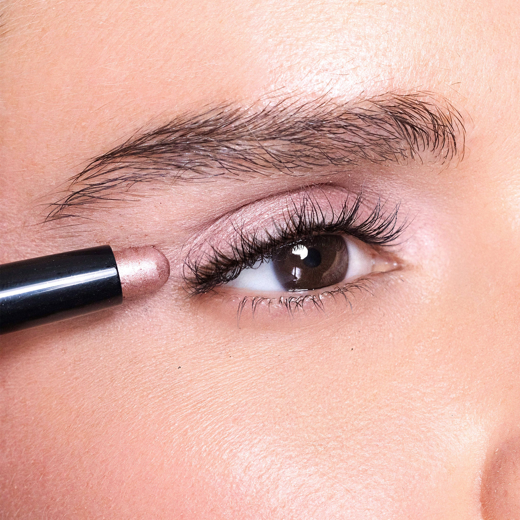 Close-up of a person applying bliss eye shadow to their eye with a pencil.