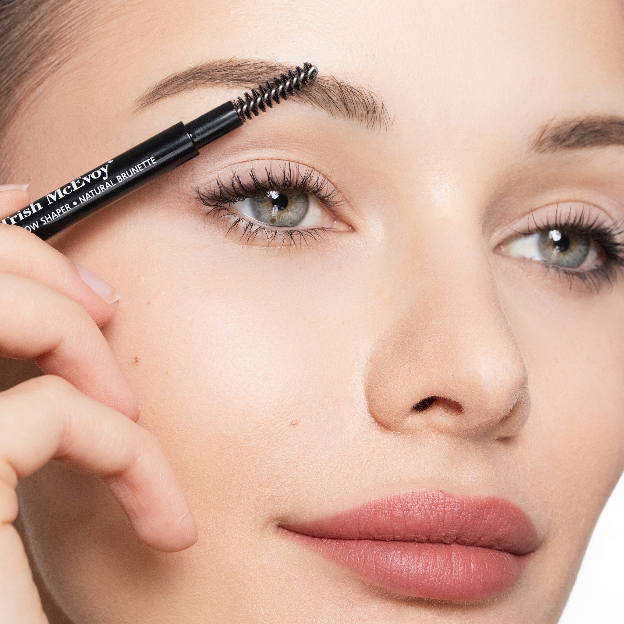 Woman applying a brow pencil to her eyebrow with a close-up focus on the product.