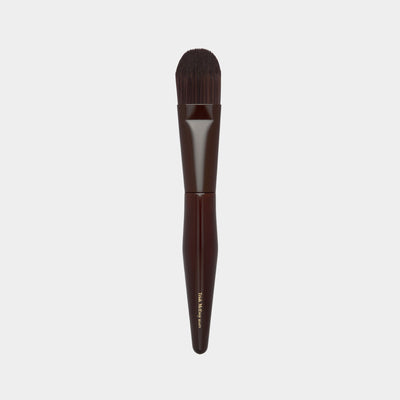 Makeup brush 75 with brown handle and black bristles on a light gray background