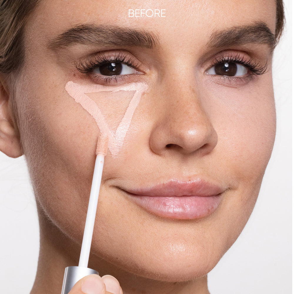 Person applying makeup with a brush on a neutral background