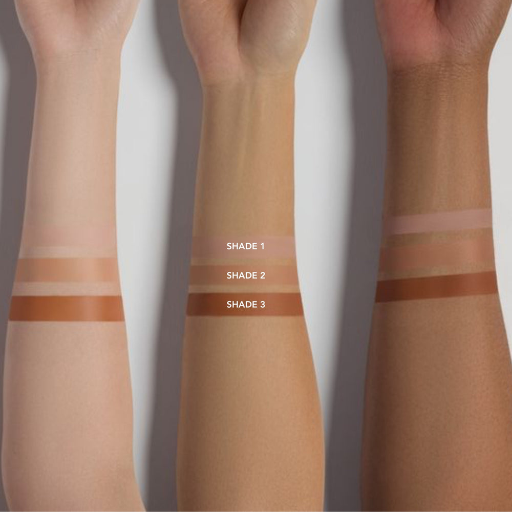 Three arms with horizontal swatches of different shades of instant eye lift on a white background