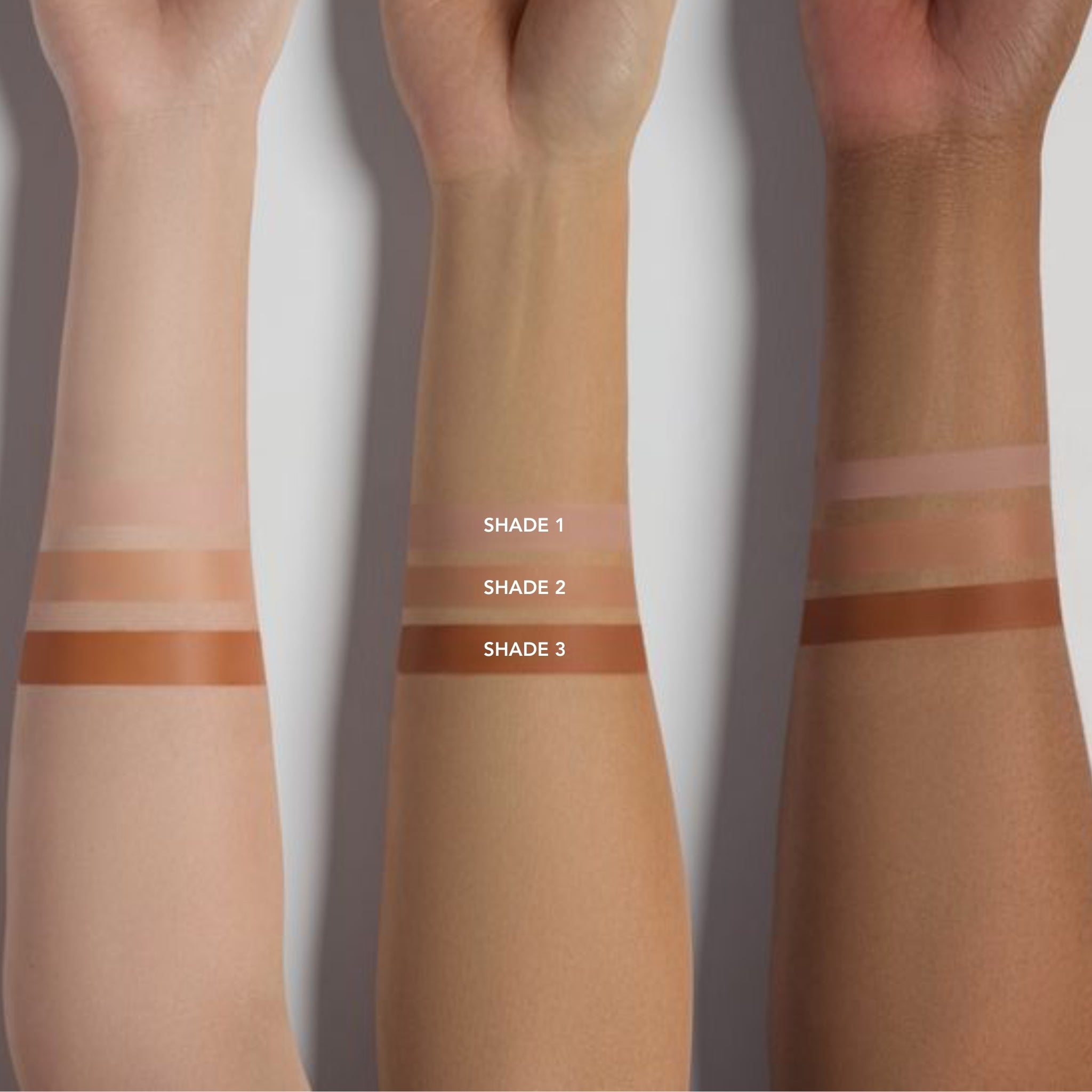 Three arms with horizontal swatches of different shades of instant eye lift on a white background