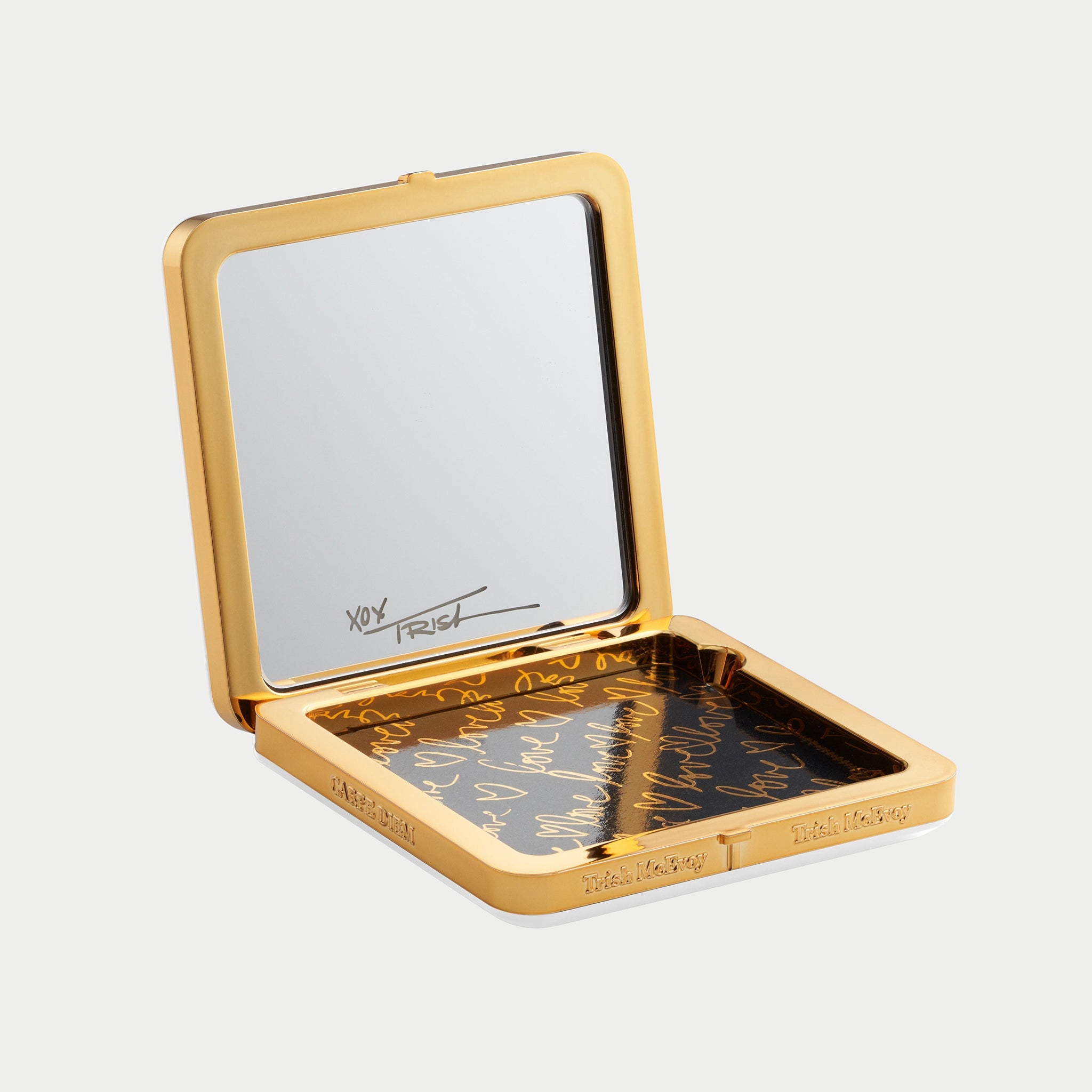 Gold compact mirror with engraved text on a light gray background