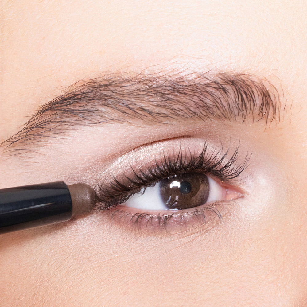 Close-up of an eye with rich color brown eyeliner being applied