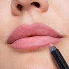 Close-up of a person applying pink lipstick with a pencil.