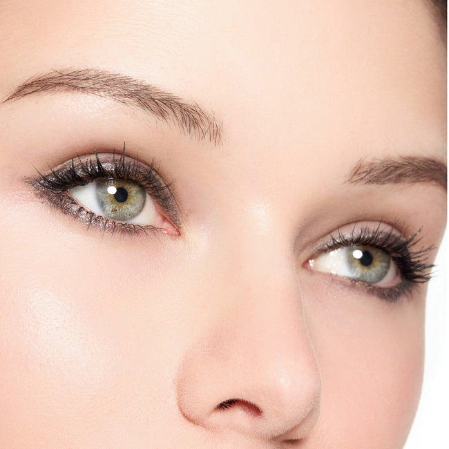 Close-up of a person's eyes with color crystal grey makeup on a white background