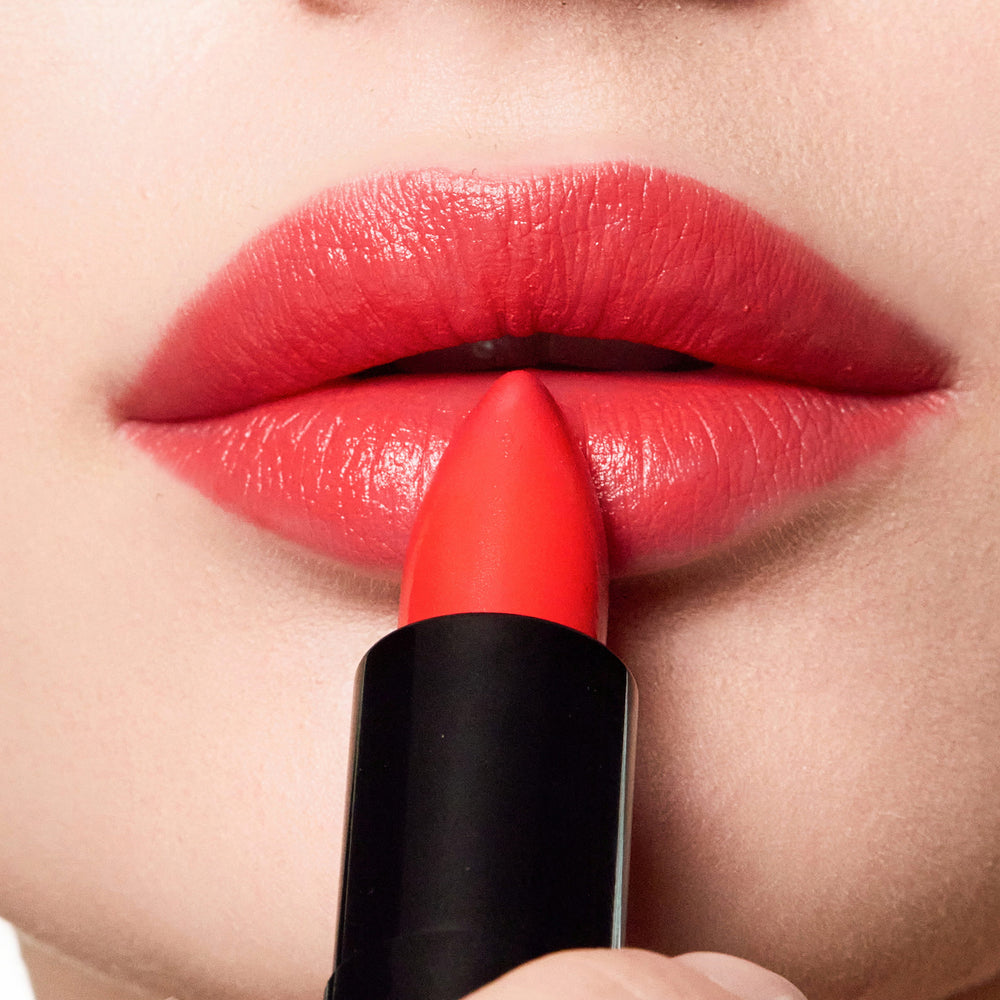 Close-up of a person applying color beautiful lipstick to their lips.