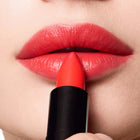 Close-up of a person applying color beautiful lipstick to their lips.