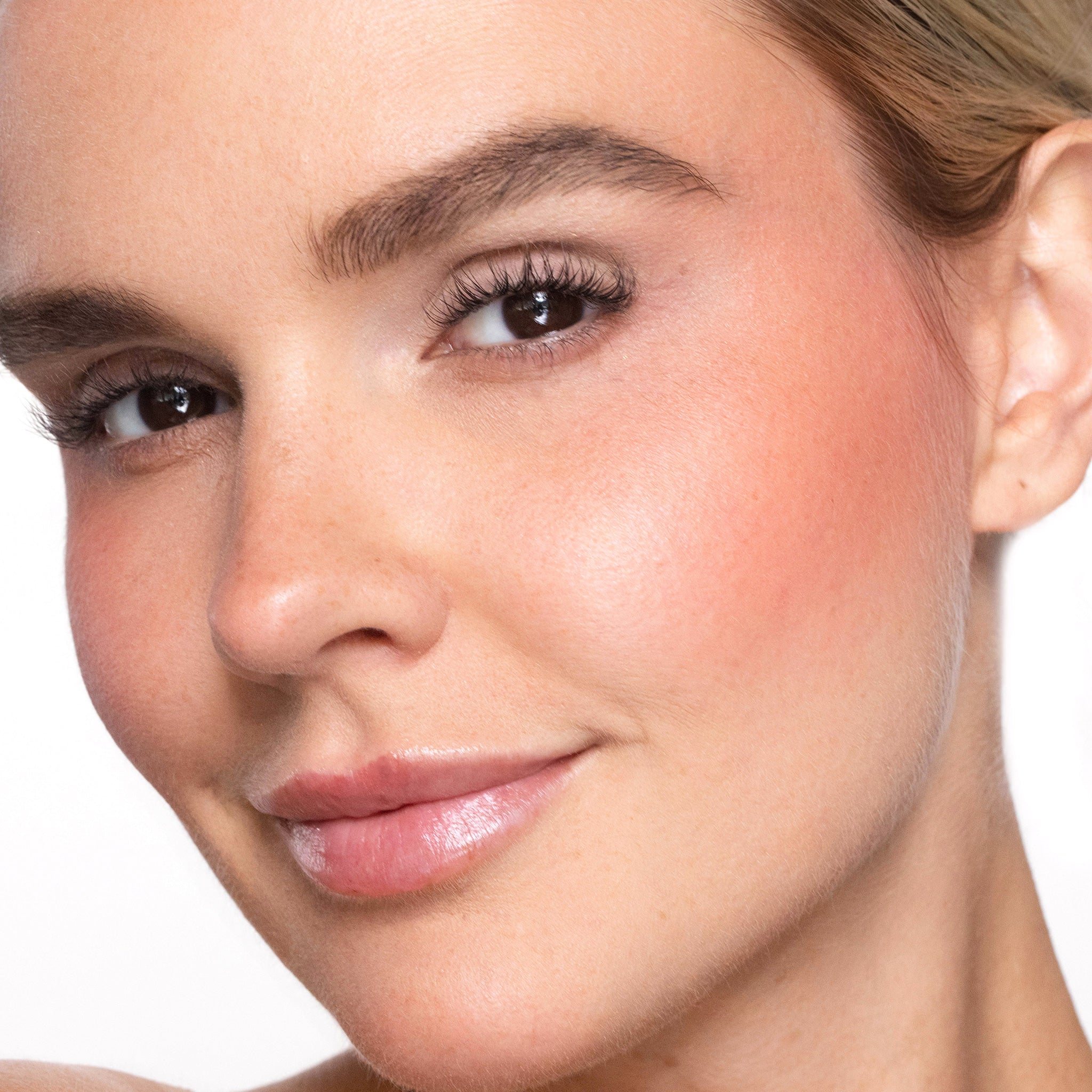 Close-up of a woman's face wearing color brighten blush  