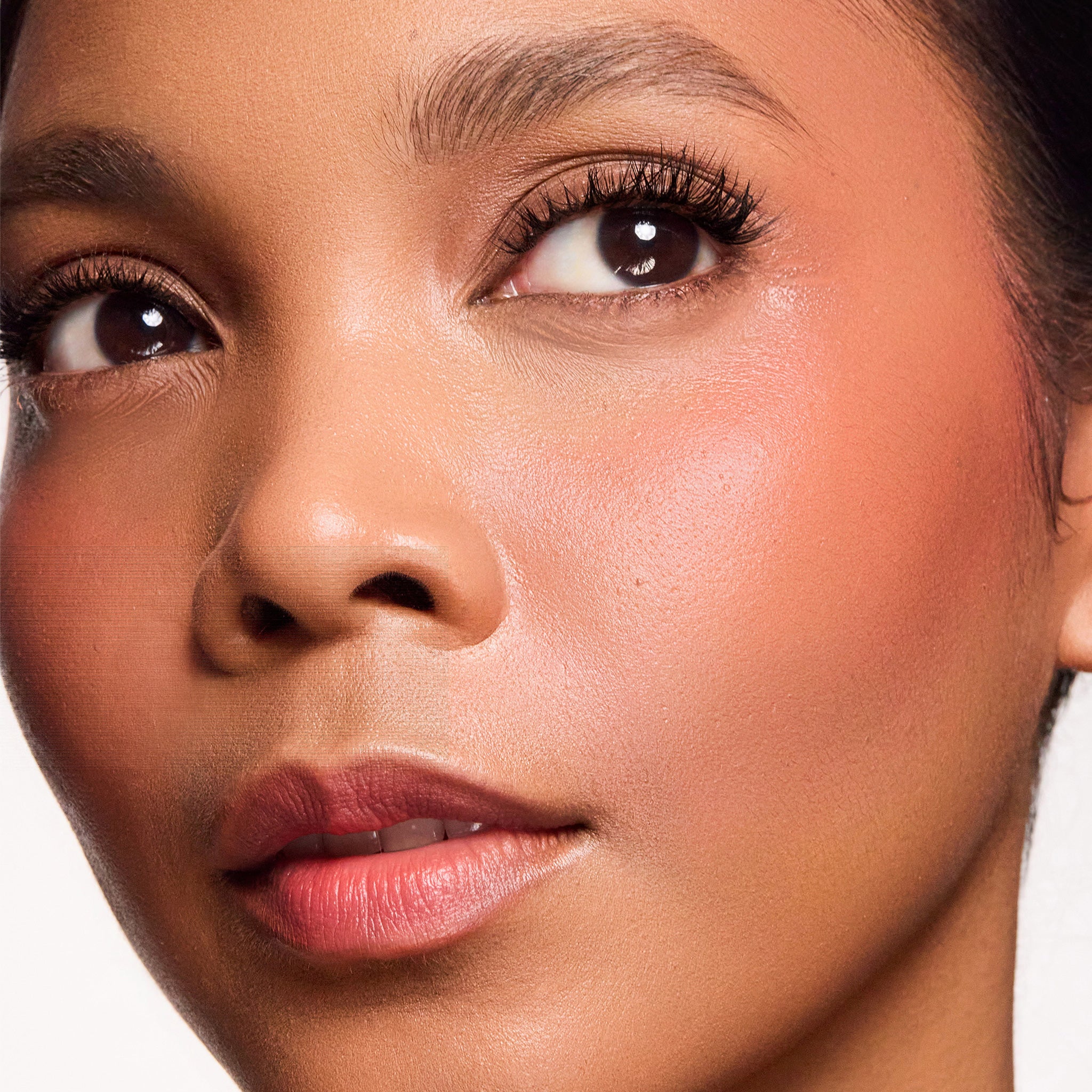 Close-up of a woman's face wearing color brighten blush  