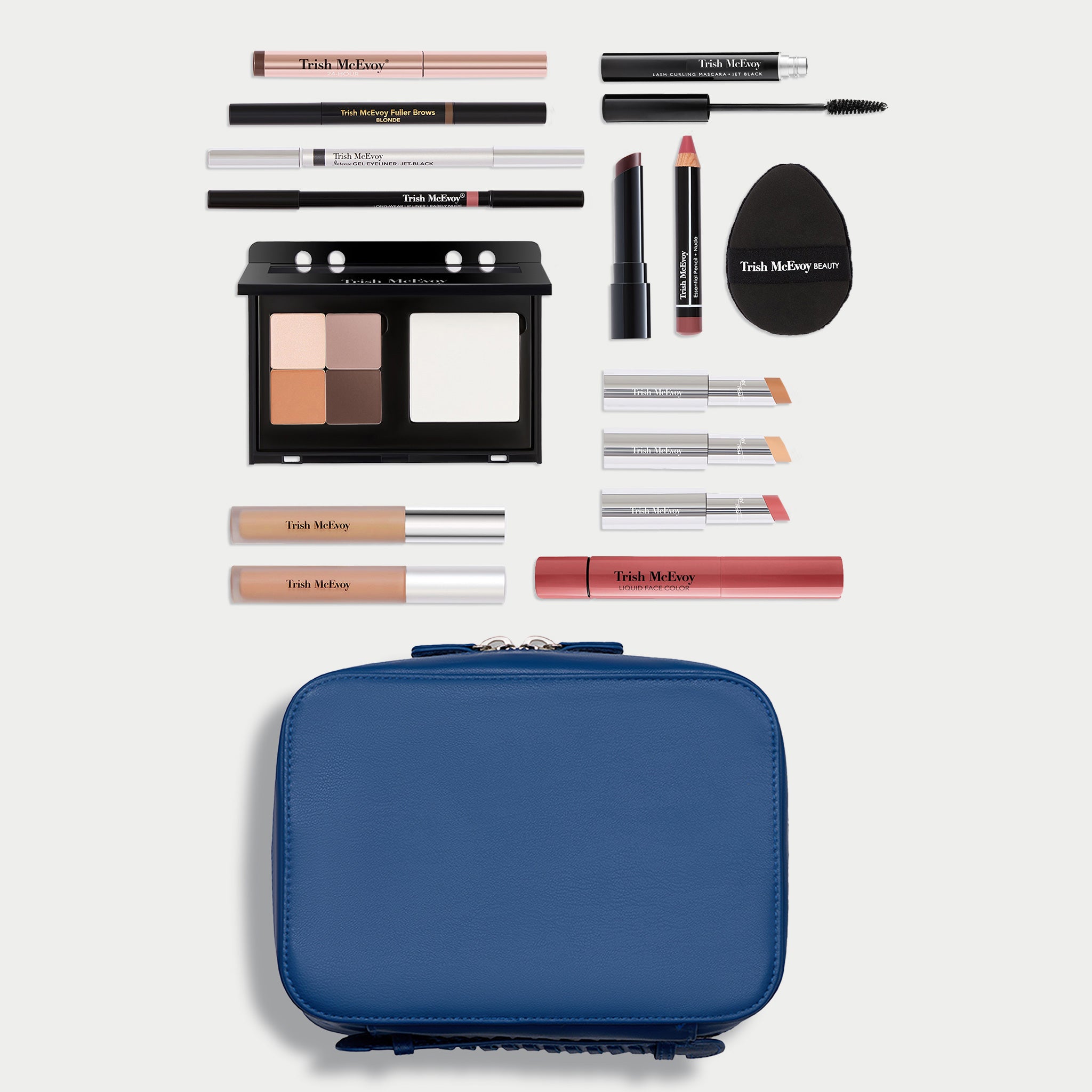 A makeup set arranged on a light gray background with a blue zippered case at the bottom and various cosmetic items above it, including eyeshadow, pencils, lip products, and a black makeup sponge. The visible brand text reads Tush Me.