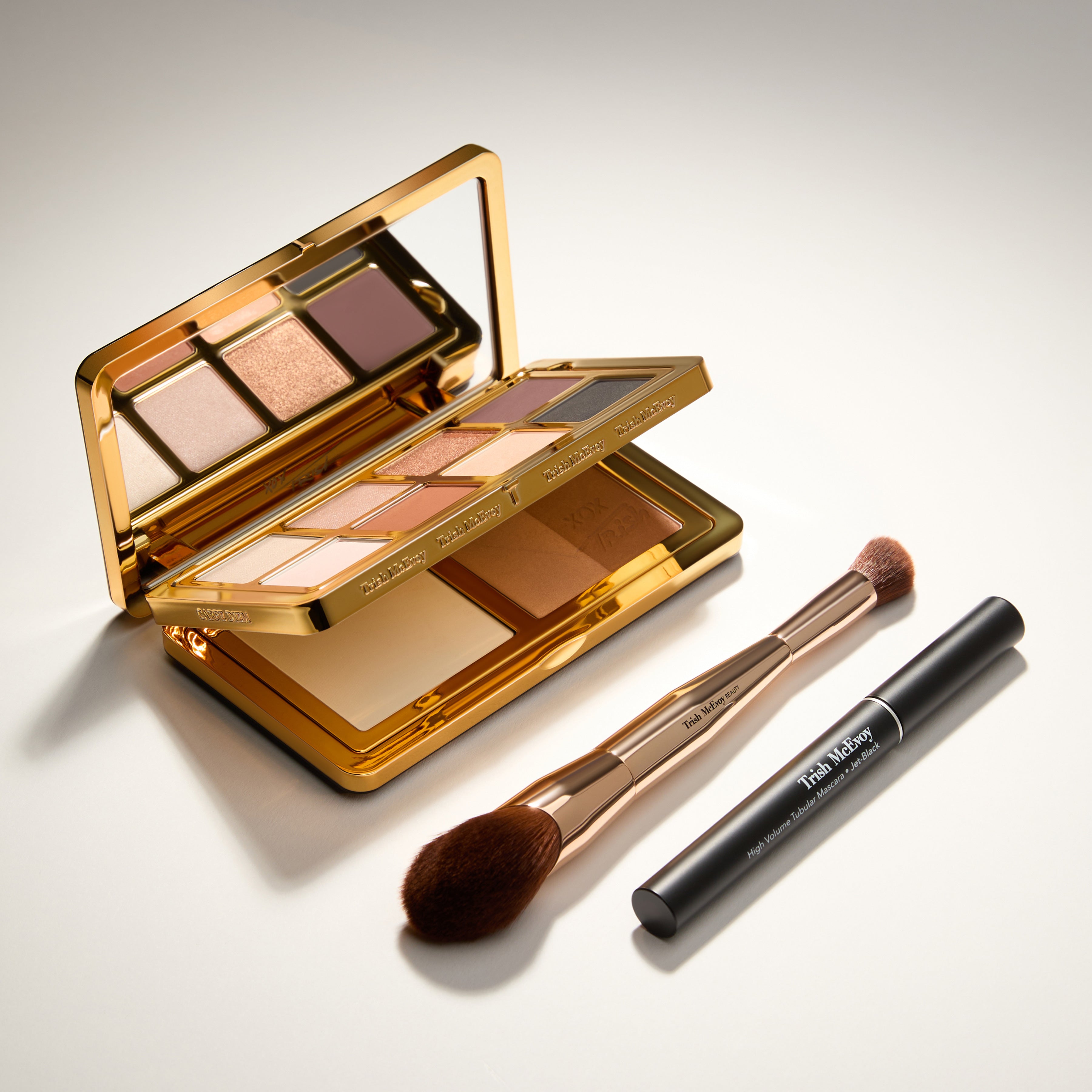 Makeup palette with brushes and mascara on a light background