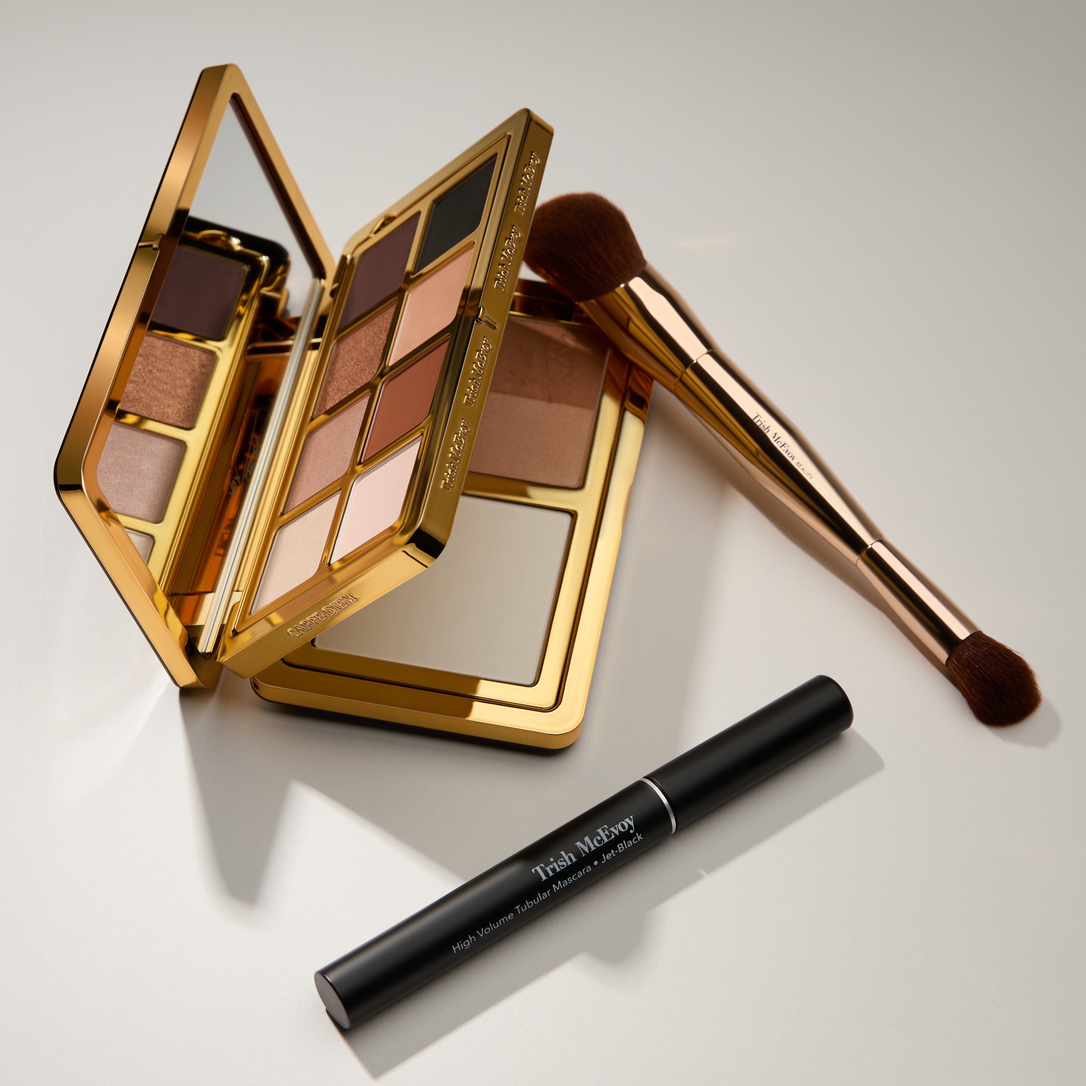 Makeup palette, brush, and eyeliner on a light gray background