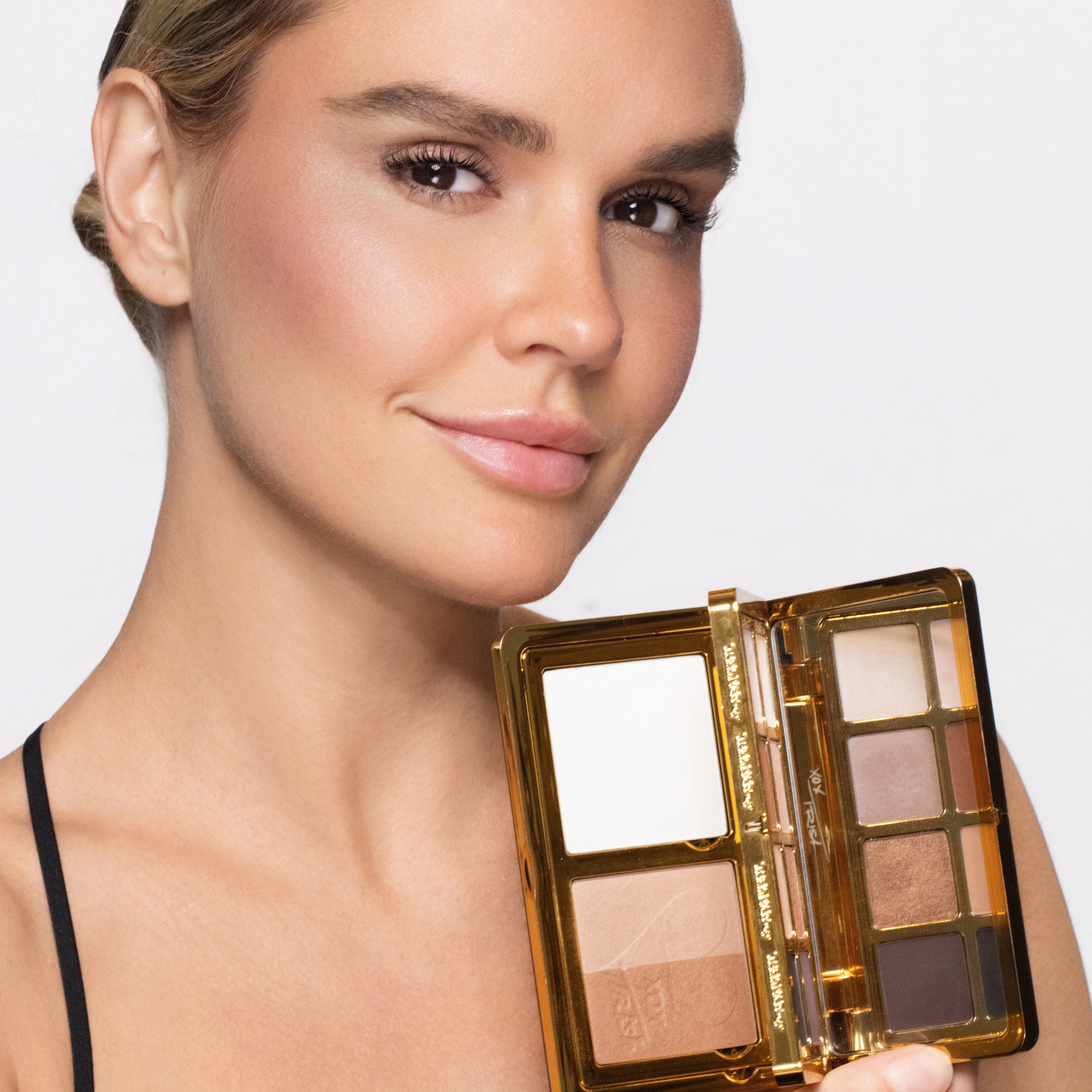 Woman holding an open makeup compact with a neutral background