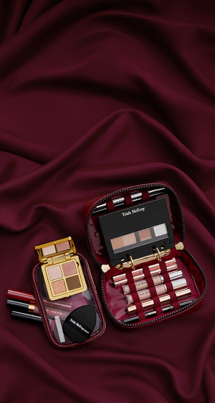 Makeup set with various products on a burgundy fabric background